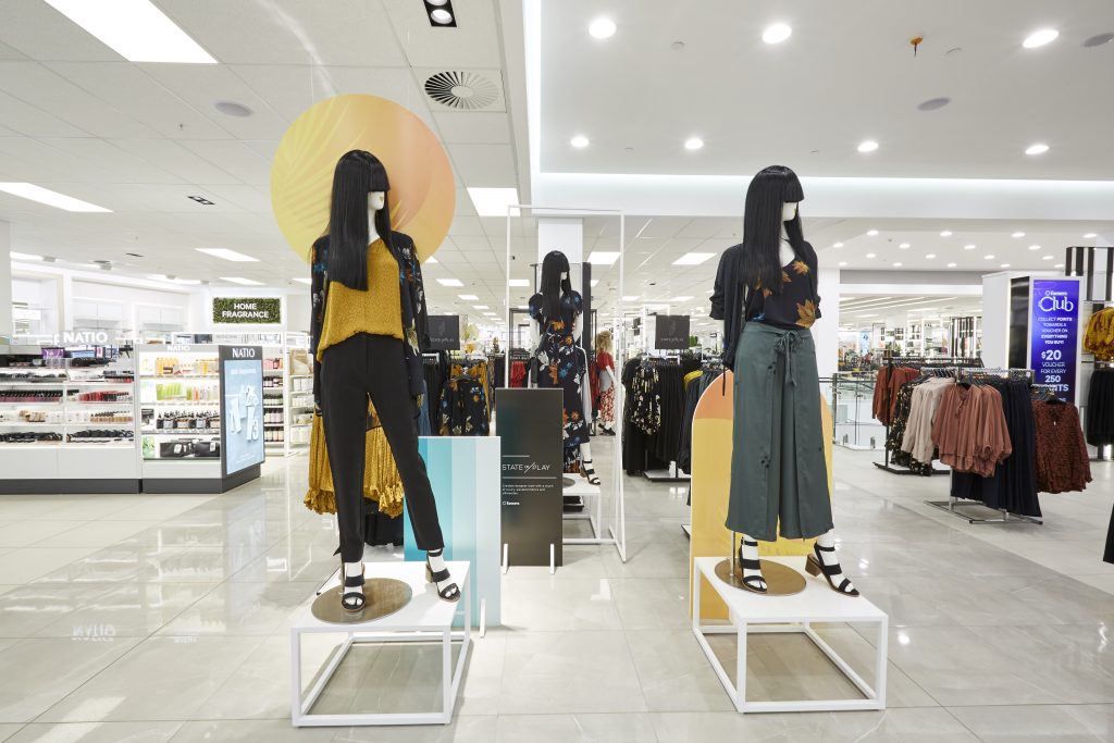 HOL Group A retail store display features three mannequins dressed in trendy outfits, perfect for the modern farmer's market. The backdrop includes clothing racks and shelves stocked with various products. The store has bright lighting and modern decor, with a variety of women's apparel on display.