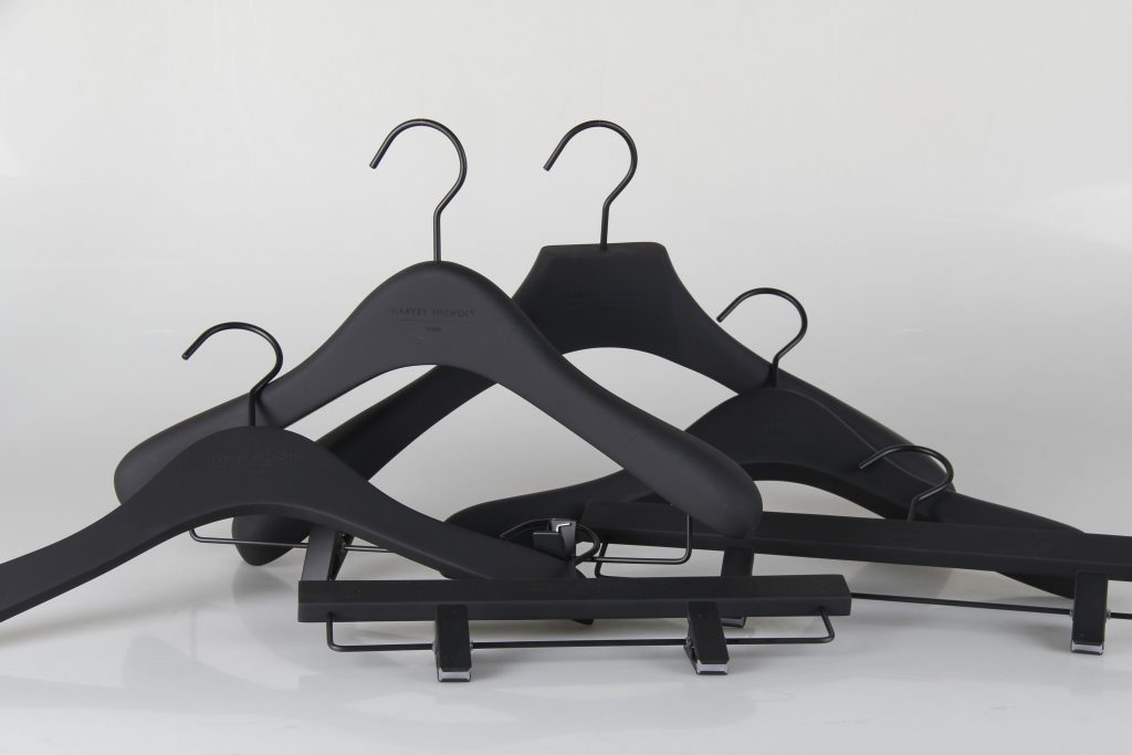 HOL Group A set of black plastic hangers, including both standard and clip hangers, are arranged in a pile against a plain white background. The hangers, available at Harvey Nichols, feature metal hooks and are designed for hanging various types of clothing.