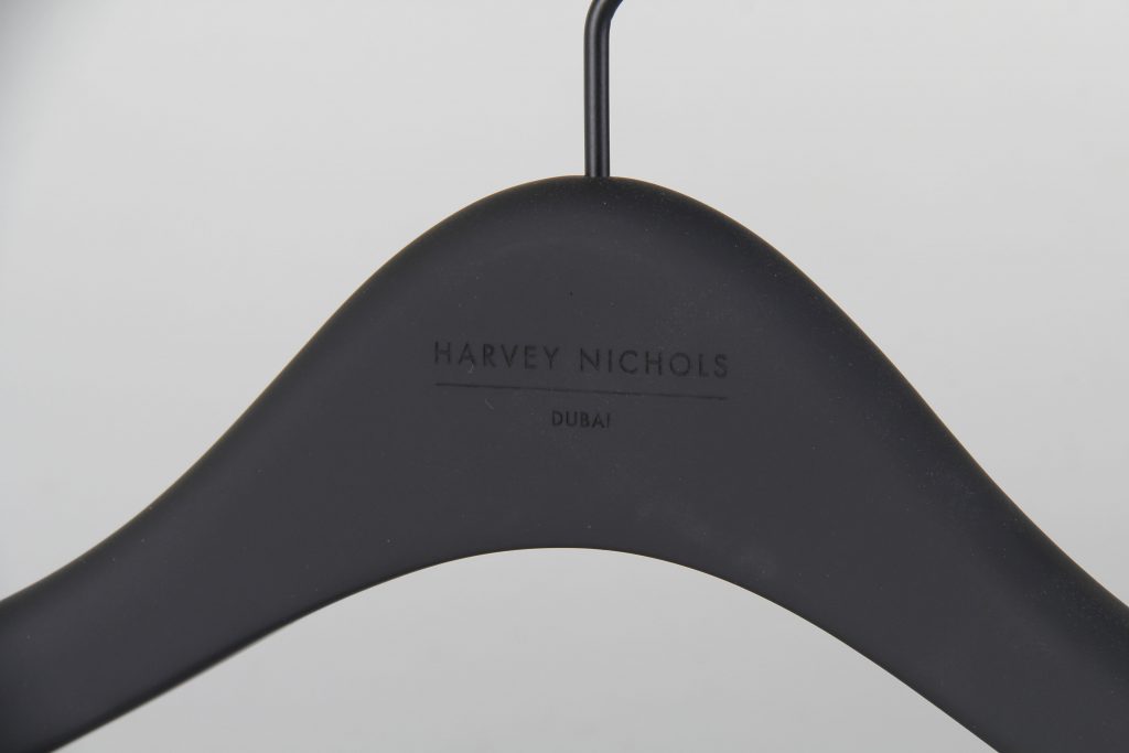HOL Group A sleek black clothes hanger adorned with the discreet text "Harvey Nichols Dubai," all set against a plain white background. This subtle yet elegant item epitomizes the sophistication of a luxury department store.